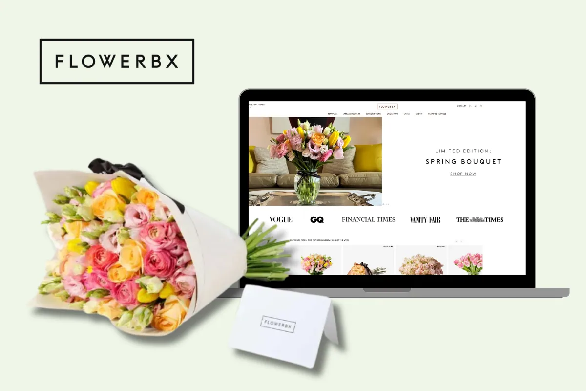 A laptop displays the website for "FLOWERBX," showcasing a "Limited Edition Spring Bouquet." To the left of the laptop is a beautifully wrapped bouquet of pink, yellow, and white flowers with some greenery peeking out. In front of the bouquet is a small white card that also says "FLOWERBX."